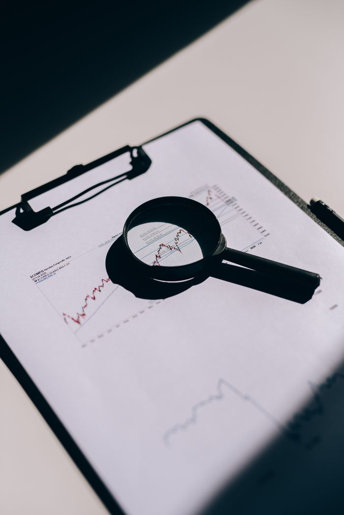The Art of Drawing Readers In: Your attractive post title goes here Detailed close-up of financial documents with graphs and magnifying glass on a clipboard.