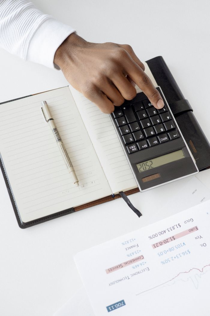 Mastering the First Impression: Your intriguing post title goes here A hand using a calculator with financial documents and notebook, depicting an office setup for financial analysis.