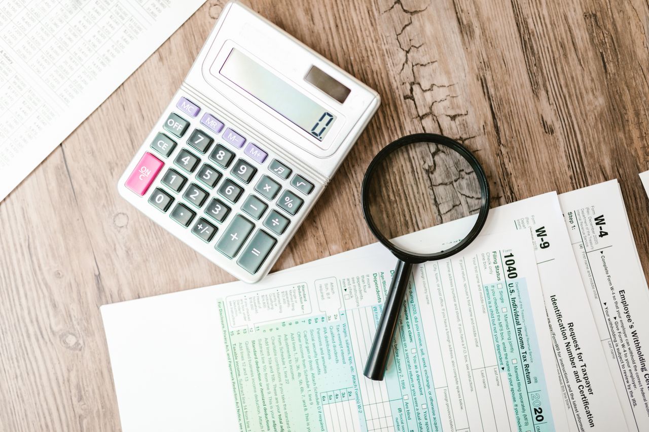 Crafting Captivating Headlines: Your awesome post title goes here Tax forms laid out with a calculator and magnifying glass on a wooden surface, perfect for finance themes.